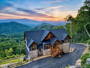 A house with a stone facade, a wooden staircase, and a view of the surrounding mountains. - Skyrise at Eagles Nest - Layered mountain views, luxury home (Banner Elk)