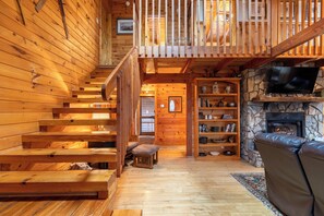 A wooden interior with a staircase, a stone fireplace, and a television. - Weathering Heights - Hot Tub, Game Room, Close to Boone and Banner Elk! (Boone)