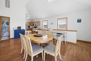 Une cuisine spacieuse avec des meubles en bois, un coin repas comprenant une table ronde et des chaises, et une petite cuisine d’appoint.