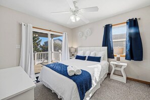 Une chambre à coucher avec un lit, une table de chevet, un ventilateur de plafond et une vue sur l’extérieur.