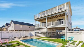 A two-story house with a pool and outdoor seating. - Perfect Break | Private Pool and Hot Tub | Less than 1,000 ft to the Beach! (Kill Devil Hills)