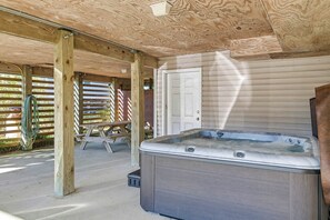 En træterrasse med jacuzzi, en dør og et picnicbord.