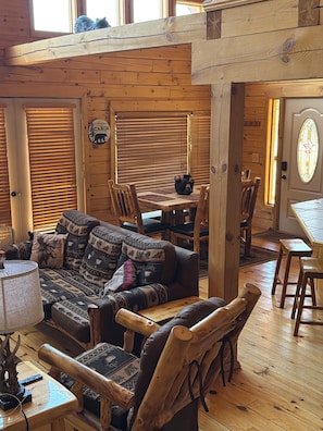 A cabin interior with a wooden dining table, a sofa with patterned cushions, and a wooden chair. - South Fork Cabin Near Wolf Creek Ski  Fishing, ATV Trails, Mountain Views (South Fork)