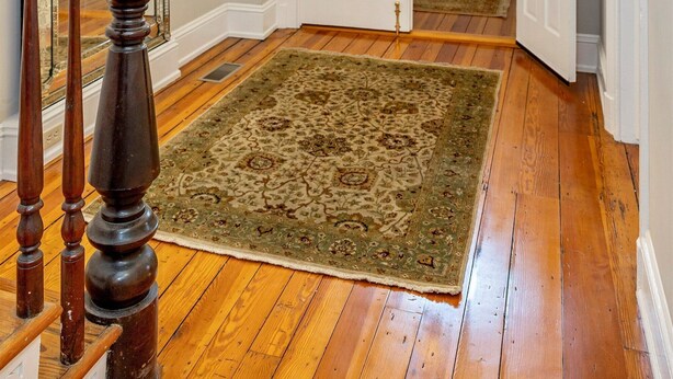 A hallway with wooden flooring, a large ornate mirror, a chandelier, and a patterned rug. - Gilded Age Getaway: Sleeps 6, free garage parking (Frederick)