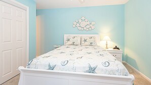 A bedroom with a bed, a ceiling fan, a wall decoration, a bedside table, and a nightstand. - Uptown OC 2 Bedroom | Pool, Sauna & Pickleball (Ocean City)