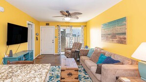 A living room with a television, sofa, coffee table, and a ceiling fan. - Uptown OC 2 Bedroom | Pool, Sauna & Pickleball (Ocean City)