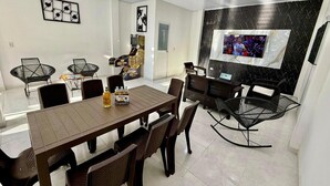 Un comedor moderno con una mesa y sillas de madera, un televisor instalado en una pared negra y un adorno mural.