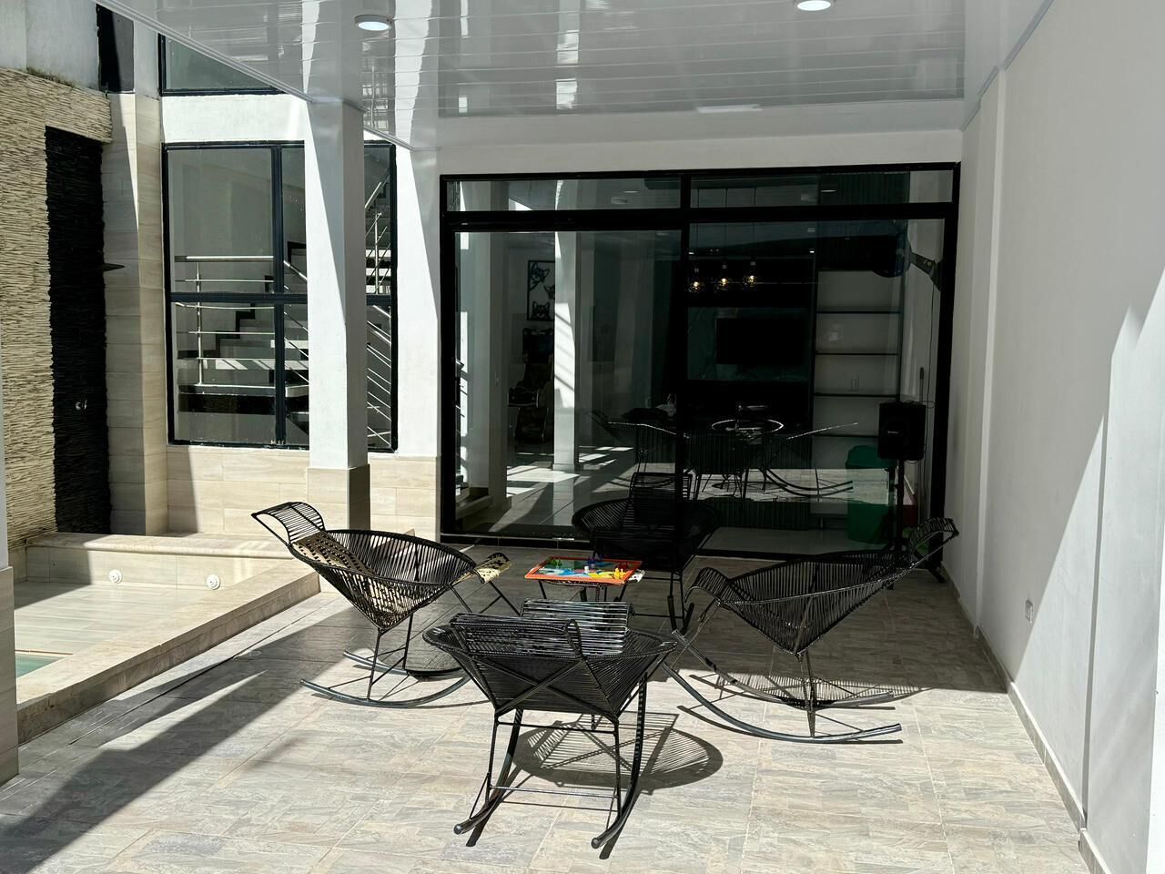 An outdoor seating area with a table and chairs, a staircase, and a glass door leading inside.