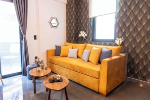 A modern living room with a sofa, two round wooden tables, and a decorative vase. - Iris One: Near Acropolis - New, Luxurious & Cozy (Athina)