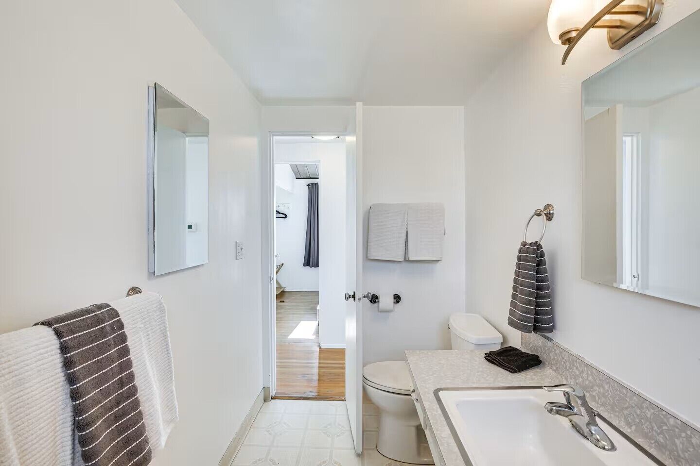 A modern bathroom with a white sink, a mirror, and a toilet.