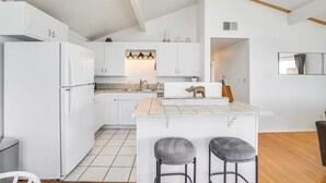A modern kitchen with white cabinets, a central island with stools, and a small seating area. - 3 bedroom condo with expansive view (San Diego)
