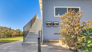 A modern building with a staircase leading to a door, a mailbox, and a well-maintained garden. - 3 bedroom condo with expansive view (San Diego)