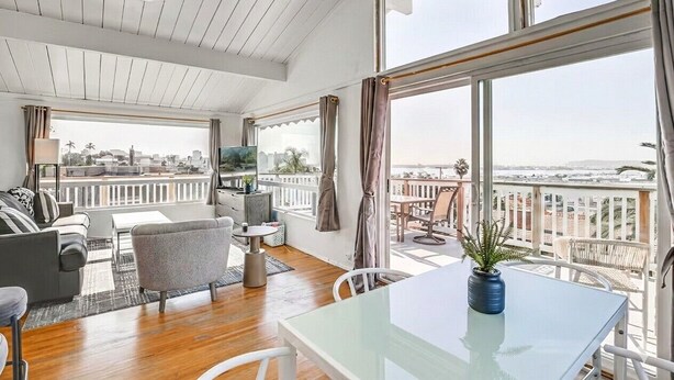 A spacious living room with a balcony, large windows, and a view of the city. - 3 bedroom condo with expansive view (San Diego)