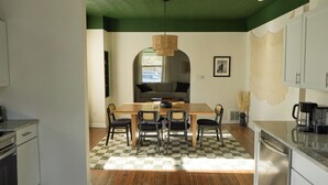 Un comedor con una mesa y sillas de madera, una lámpara colgante y un tapete de cuadros.