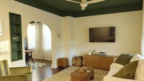Una sala de estar con sofá, mesa de centro y televisor de pantalla plana en la pared.