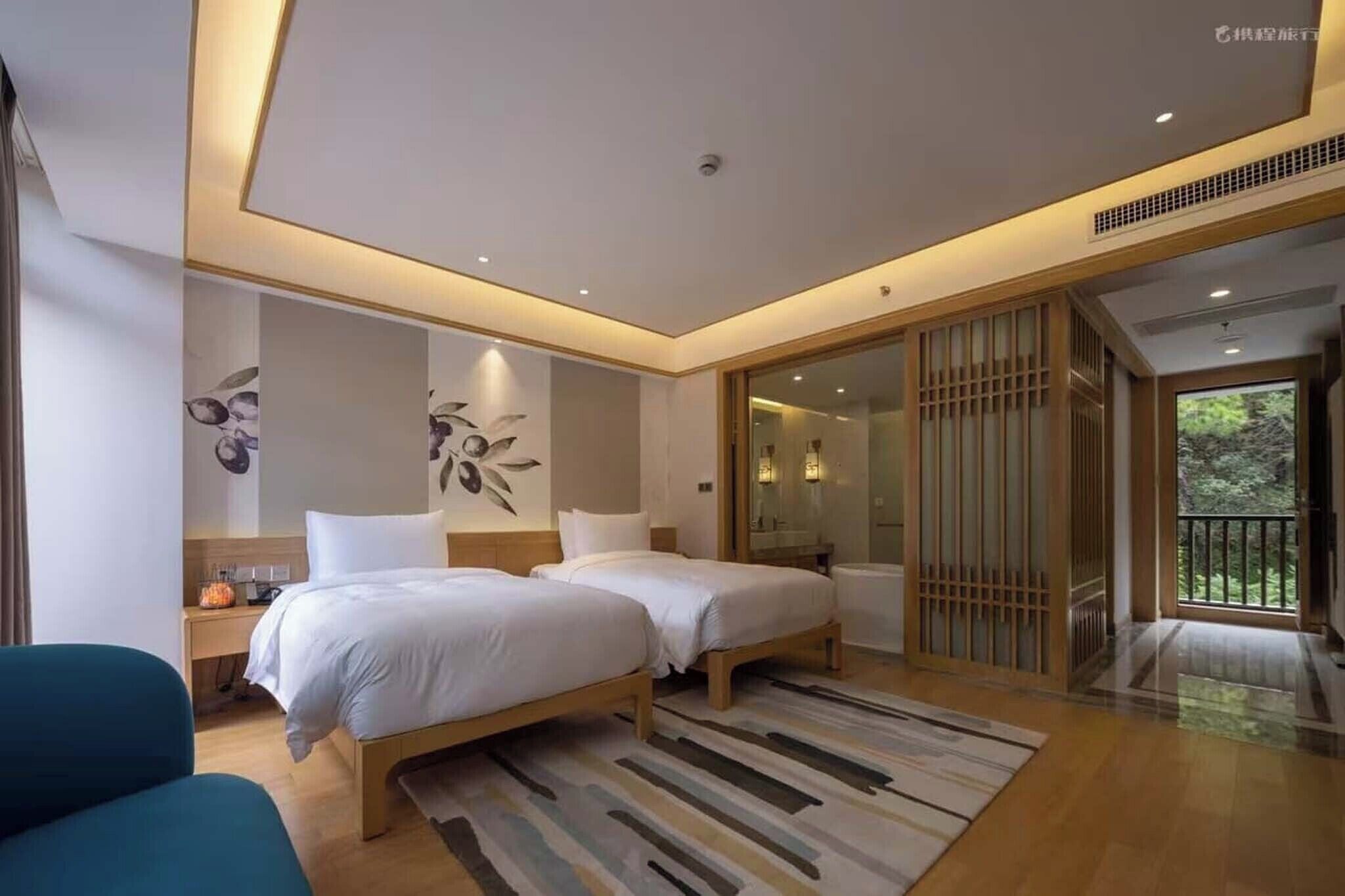 A modern hotel room with two beds, a large window, and a sliding door leading to a balcony.