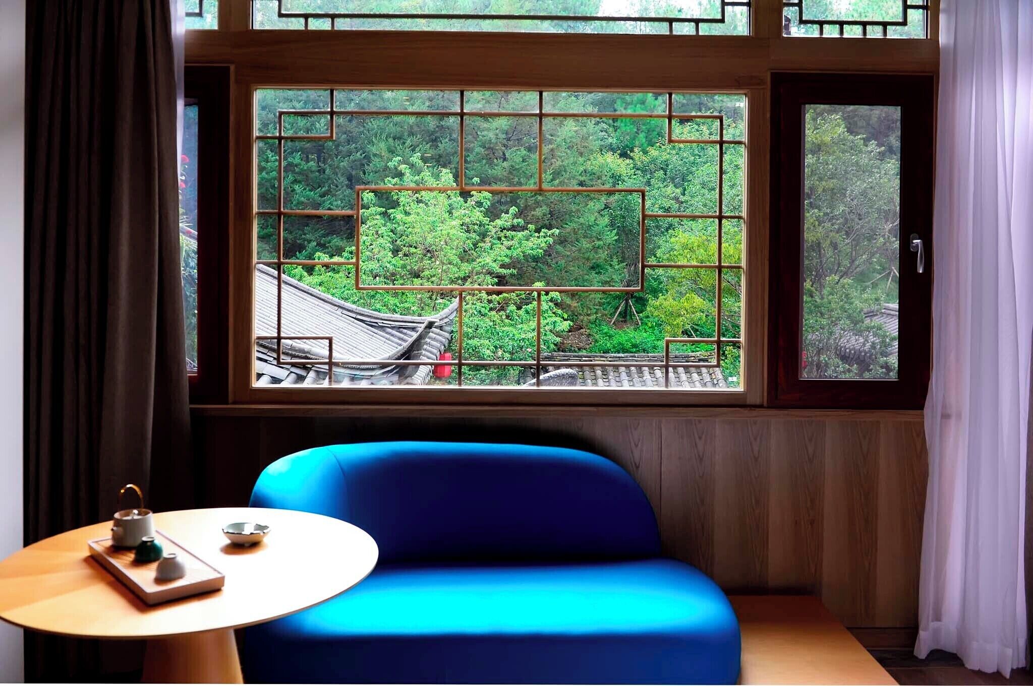 A room with a traditional-style window, a blue sofa, and a small table with a teapot and cup.