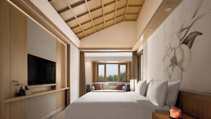 Une chambre d’hôtel moderne dotée d’un grand lit, d’un téléviseur intégré et d’une œuvre d’art fixée au mur.