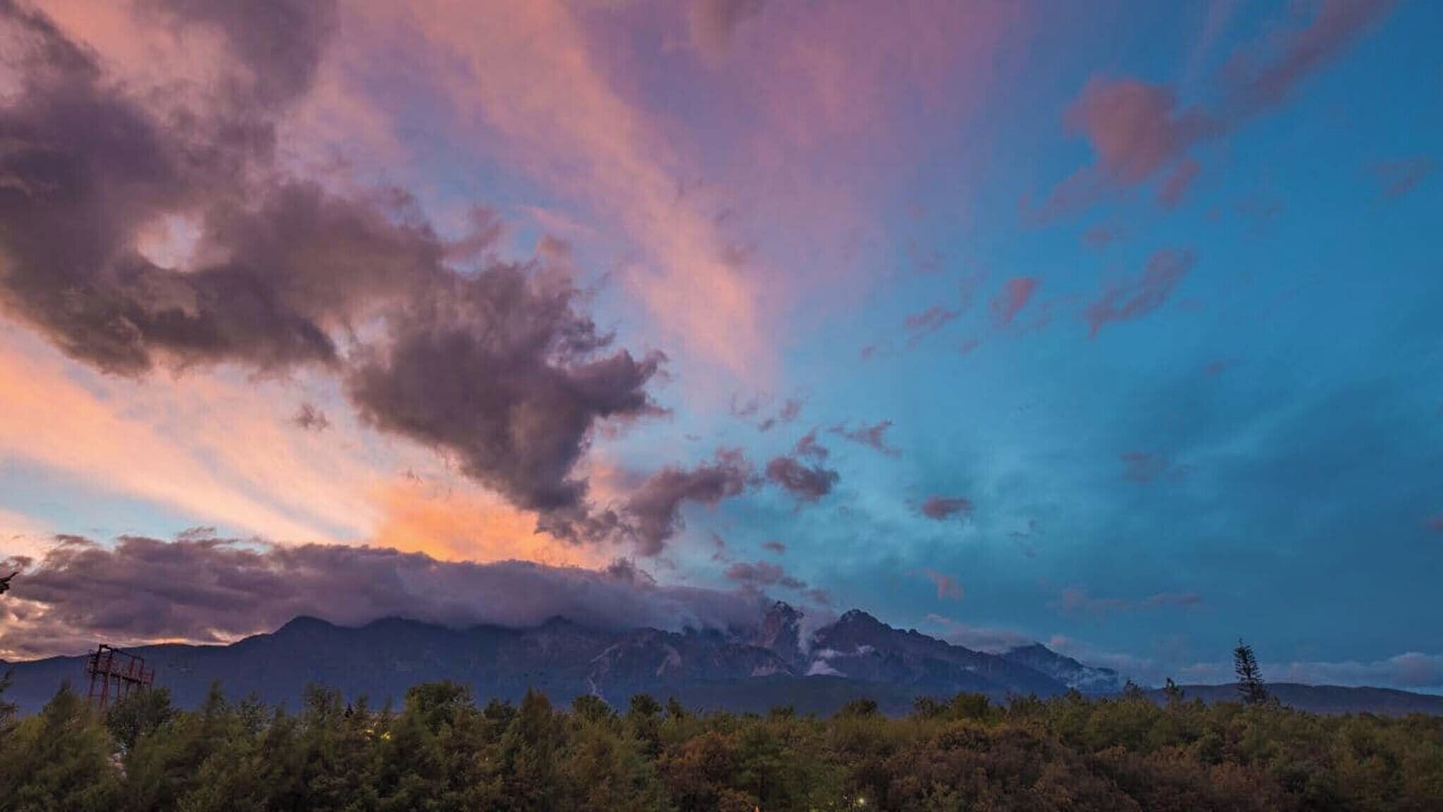 Une chaîne de montagnes sous un ciel au coucher du soleil.