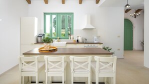 A modern kitchen with white cabinetry, a wooden island with chairs, a green window, and a green door. - Villa Kaia (Istria - Kringa) (Kringa)
