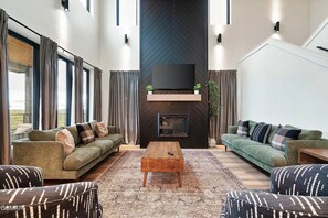 Ein geräumiges Wohnzimmer mit zwei Sofas, einem Couchtisch und einem an der Wand montierten Fernseher.
