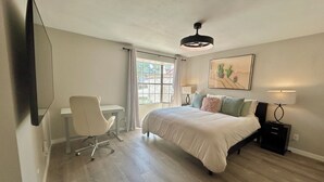 Une chambre à coucher comprenant un lit, un bureau, une chaise et un ventilateur de plafond.