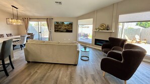 Un salon moderne comprenant un canapé, des fauteuils, une table à manger et un ventilateur de plafond.