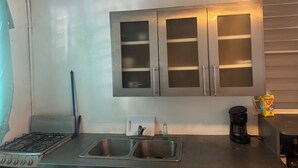 Une cuisine équipée d’une cuisinière à gaz, d’un évier à deux bacs et d’une machine à café.
