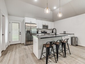 A modern kitchen with white cabinets, stainless steel appliances, and a central island with bar stools.