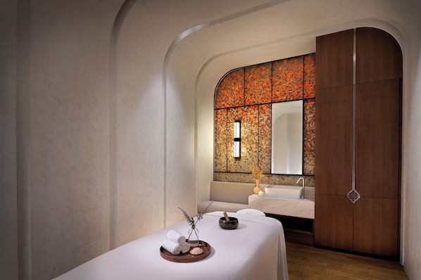 Une salle de spa équipée d’une table de massage, d’un lavabo et d’un grand miroir.
