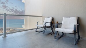 Un balcon avec deux fauteuils à bascule, une petite table et un verre de bière.