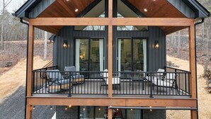Una casa moderna de dos pisos con terraza de madera y mobiliario exterior.