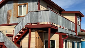 A two-story house with a red and beige exterior, a wooden staircase, and a metal balcony. - Rustic 1-bedroom studio in Emigrant near Yellowstone N.P. and Chico Hot Springs (Emigrant)