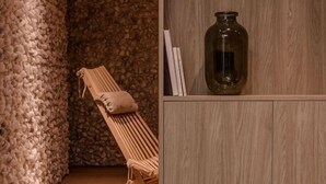 A room with a wooden bench, a stone wall, and a cabinet with a jar. - Plantonia Aparthotel (Kraków)