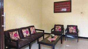A living room with two sofas and two armchairs, a coffee table, and a wall-mounted light fixture. - Homely Guest House Tegal (Tegal)