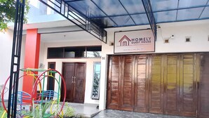 A modern guest house with a glass ceiling, a signboard, and a wooden door. - Homely Guest House Tegal (Tegal)