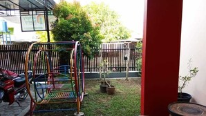 A patio area with a swing set, potted plants, and a Yamaha motorcycle. - Homely Guest House Tegal (Tegal)