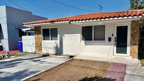 A single-story house with a tiled roof, a front door, and a small porch area. - Family Home in the Heart of Miami (Miami)