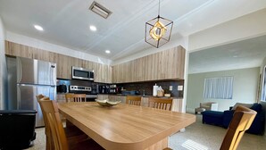 A modern kitchen with wooden cabinets, stainless steel appliances, and a dining area with a wooden table and chairs. - Family Home in the Heart of Miami (Miami)