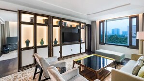 A modern hotel room with a large TV, seating area, and a view of the city. - The Grand Mansion Hotel (Nanjing)