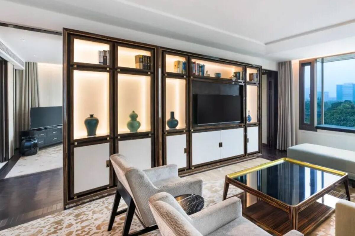 Een moderne hotelkamer met een grote televisie, zithoek en uitzicht op de stad.