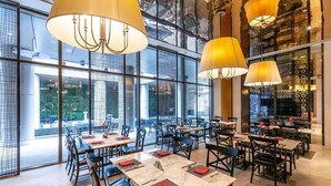 A modern restaurant with large windows, multiple dining tables, and hanging lamps. - The Grand Mansion Hotel (Nanjing)