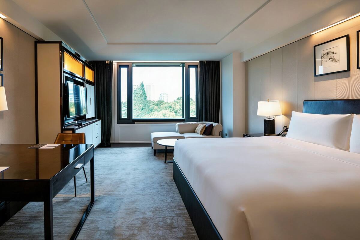 Een hotelkamer met een groot bed, een bureau met een computer, een stoel, een bank en een televisie.