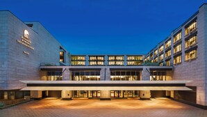 A modern hotel with a prominent entrance, multiple floors, and a well-lit facade. - The Grand Mansion Hotel (Nanjing)