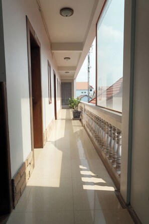 A corridor with a tiled floor, wooden doors, and a potted plant. - Dara Panha Sak Guesthouse (Siem Reap)