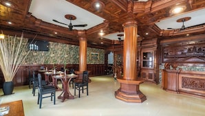 Een ruime lobby met hoge houten plafonds, een ronde centrale tafel met stoelen, en een grote zuil.
