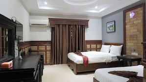 Een hotelkamer met een bed, bureau, spiegel en raam met gordijnen.