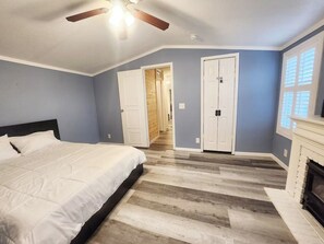 A bedroom with a bed, a fireplace, and a hallway leading to another room. - Spacious 4-bedroom house with pool in the hills of Leander (Leander)