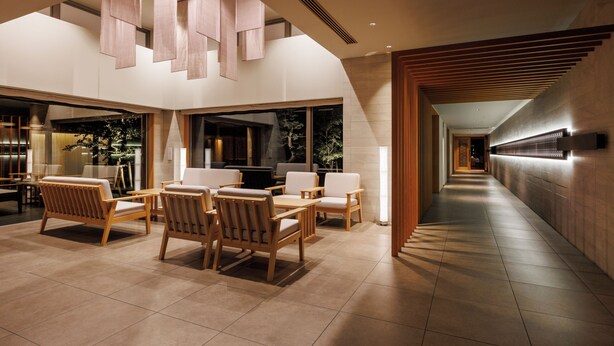 A modern interior with a dining area featuring wooden furniture and a long corridor with a wooden slat wall. - AUBERGE de SENVIE (Sakurai)