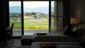 A hotel room with a large window offering a view of a green landscape and mountains. There is a bed and a desk with a chair. - AUBERGE de SENVIE (Sakurai)